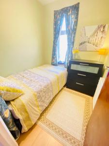 a bedroom with a bed with a dresser and a window at Your Cosy and Welcoming HomeStay!! in Ilford