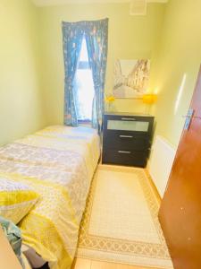 a bedroom with a bed and a dresser and a window at Your Cosy and Welcoming HomeStay!! in Ilford