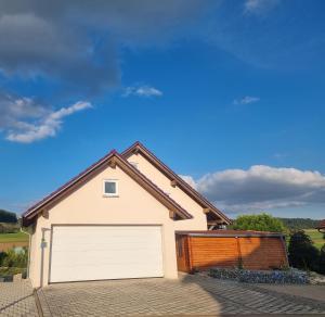 een vrijstaand huis met een witte garage bij Ferienwohnung Biosphärenblick in Münsingen