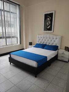 a bedroom with a large bed with blue and white sheets at La Gran Mansión en el corazón de Pereira in Pereira