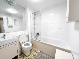 uma casa de banho branca com um WC, uma banheira e um lavatório. em Lovely 2 bedroom flat with free parking, great transport links to Central London, the Excel Centre, Canary Wharf and the O2! em Londres