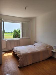 1 dormitorio con cama y ventana grande en Un séjour à la campagne en Courpignac