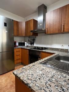 een keuken met houten kasten en een roestvrijstalen koelkast bij Villa Eclips in Playa Blanca