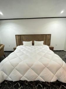 a large white bed with a large white comforter at Rafsal A Countryside Cottage in Skardu