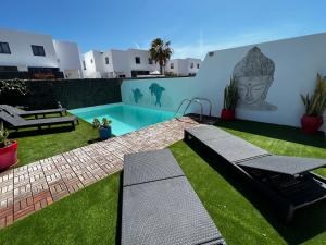 een achtertuin met een zwembad en groen gras bij Villa Eclips in Playa Blanca