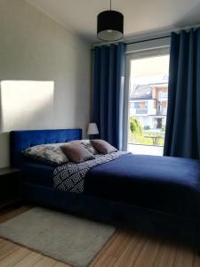 a bedroom with a blue bed and a window at Apartament Sand&Blue in Sztutowo