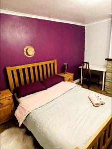 1 dormitorio con 1 cama grande y pared morada en Mia Property 2 en Bristol