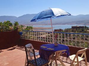 a table and chairs with an umbrella on a balcony at Abla room in Azilal