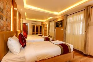 a hotel room with three beds and a television at Hotel Elegant Kathmandu Inn in Kathmandu