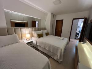 a hotel room with two beds and a television at Beach Place - Apartamento 03 decorado a 100m da Praia do Cumbuco in Cumbuco