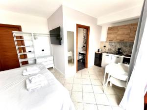 a bedroom with a white bed and a kitchen at Cape House in Albano Laziale