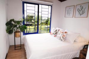 Cama blanca en habitación con ventana en Villas Alto Bonito, en Sevilla
