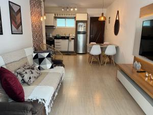 een woonkamer met een bank en een keuken bij Beach Place - Apartamento 03 decorado a 100m da Praia do Cumbuco in Cumbuco