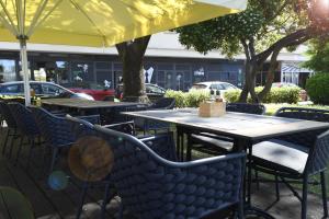 an outdoor patio with tables and chairs under a yellow umbrella at Il Padrino Rooms in Zadar