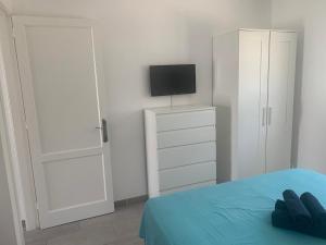 een slaapkamer met een bed en een televisie en kasten bij La Perla de S.Valentin in Corralejo