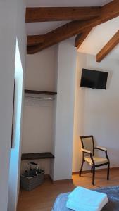 a bedroom with a bed and a chair and a tv at Hostal A Cantina de Renche 