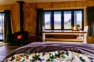 1 dormitorio con 1 cama, chimenea y ventana en Fiery Peak Eco-Retreat, en Geraldine