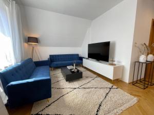 ein Wohnzimmer mit einem blauen Sofa und einem TV in der Unterkunft Design Maisonette I Kamin I 10 Personen I Netflix in Bremen