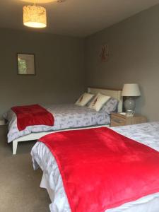 a bedroom with two beds and a red blanket at Little Hare Lodge - Spacious 2 bedroom attached bungalow in Woodhall Spa