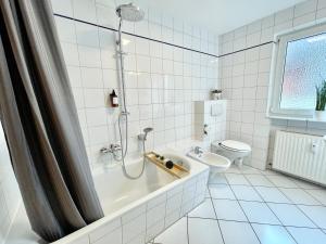 a white tiled bathroom with a shower and a toilet at Design Maisonette I Kamin I 10 Personen I Netflix in Bremen