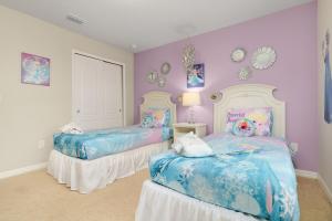 2 camas en una habitación con paredes rosas y moradas en A Whole New World Villa, en Kissimmee