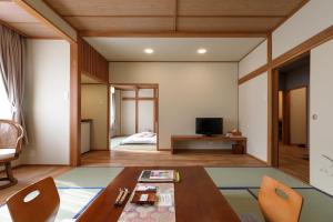 un soggiorno con tavolo e una camera da letto di Tsukasaya Ryokan a Tsuruoka