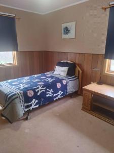 een slaapkamer met een bed met een blauwe deken erop bij Vinegar Hill Airbnb in Bridgetown