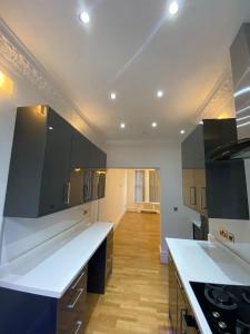 Luxury Apartment with a jacuzzi في ولفرهامبتون: مطبخ كبير مع قمم منضدة بيضاء وخزانة سوداء