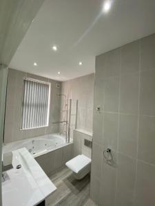 a bathroom with a tub and a toilet and a sink at Luxury Apartment with a jacuzzi in Wolverhampton