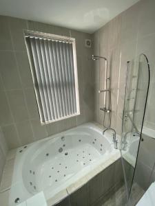 a white bath tub in a bathroom with a window at Luxury Apartment with a jacuzzi in Wolverhampton