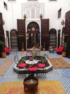 une cour avec des chaises rouges et une table dans un bâtiment dans l'établissement Dar Al Batoul, à Fès