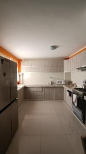 a large kitchen with a refrigerator and a stove at Renacer apartamentos in Tacna