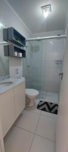 a bathroom with a toilet and a glass shower at Apartamento clube próximo à praia in Caraguatatuba