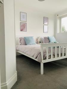 a bedroom with a white bed with pink and blue pillows at Greenshaw 3 Bedroom Terrace in Brentwood