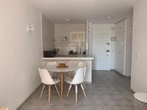 een keuken met witte stoelen en een tafel en een aanrecht bij Benalmadena Jupiter Ocean View Apartament in Benalmádena