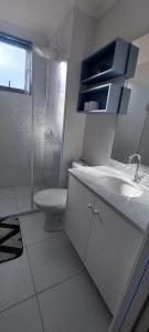 a white bathroom with a sink and a toilet at Apartamento clube próximo à praia in Caraguatatuba