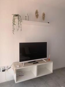 een flatscreen-tv zittend op een wit entertainment center bij Benalmadena Jupiter Ocean View Apartament in Benalmádena