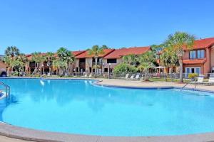 a large swimming pool at a resort with palm trees at Sandcastles and Sunshine - Gulf Highlands Beach Resort in Panama City Beach
