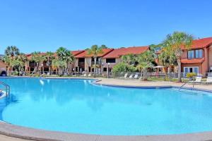 - une grande piscine dans un complexe avec des palmiers dans l'établissement Sandcastles and Sunshine - Gulf Highlands Beach Resort, à Panama City Beach