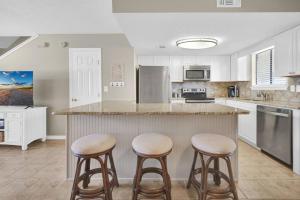 a kitchen with white cabinets and stools at a counter at Sandcastles and Sunshine - Gulf Highlands Beach Resort in Panama City Beach