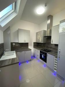a kitchen with white cabinets and blue lights in it at Penthouse APT8 in Wolverhampton