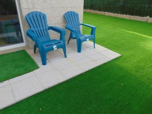 Duas cadeiras azuis sentadas num pátio com relva verde em apartamento con jardin em Santiago de Compostela