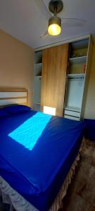 a blue bed in a bedroom with a closet at Apartamento clube próximo à praia in Caraguatatuba