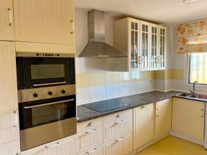 uma cozinha com armários brancos e electrodomésticos de aço inoxidável em People Homes Bajo Guía em Sanlúcar de Barrameda