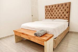 Casa Centro Guaduas في غوادواس: غرفة نوم بسرير كبير ومقعد خشبي