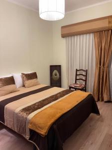 a bedroom with a large bed and a chair at Guest House “Casa da avó Tina” in Barreiro