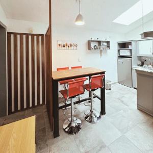 a kitchen with a wooden table and red stools at Departamento tipo LOFT cerca de hospital Angeles in Mexico City