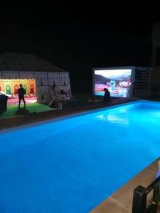 una piscina con TV en el fondo en American Farm Villa Grand Casablanca/El Jadida 