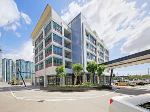 a large white building in a parking lot at Link Portside Wharf Apartment Hotel in Brisbane
