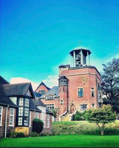 a large brick building with a clock tower on it at The Snug@Bournville in Birmingham